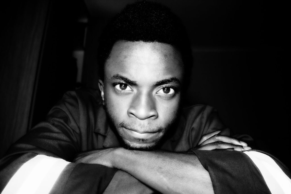 Intense black and white portrait of a man indoors, focused expression.